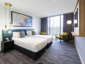 a hotel room with a large bed and a chair at Mercure Canberra Belconnen in Canberra +84 photos