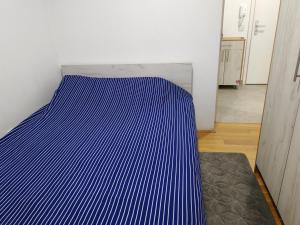 a bed in a room with a blue and white stripes at Apartman 40 in Modriča