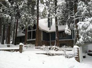 a snow covered house with a fence and trees at Chateau Bernina in Lake Arrowhead