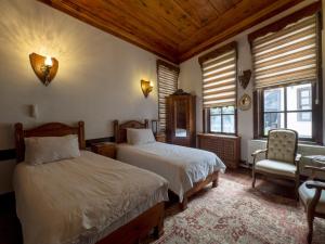 a bedroom with two beds and a chair and windows at AKİFBEY KONAĞI in Kastamonu