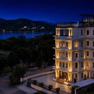 a building with its lights on at night at The Colonial - A Lake View Hotel in Udaipur in Udaipur