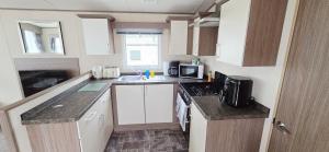 a small kitchen with white cabinets and a sink at The Minver - Park Dean Resort in Saint Minver