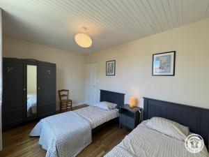 a bedroom with two beds and a table with a lamp at Gîte brisset in Coulaures