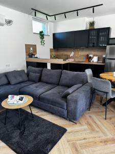 a living room with a blue couch and a kitchen at Dominó Apartman in Gelse