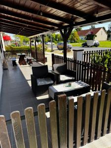 a patio with chairs and tables and a wooden pergola at Dominó Apartman in Gelse