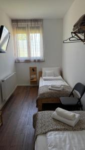 a room with three beds and a chair in it at Dominó Apartman in Gelse