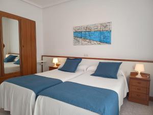 a bedroom with a large bed with blue pillows at Pensión Bella Vista in Cóbreces
