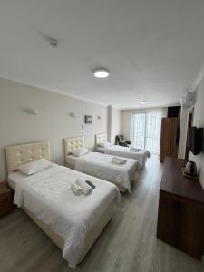 three beds in a room with white walls and wooden floors at LUXOR RESIDENCE in Trabzon
