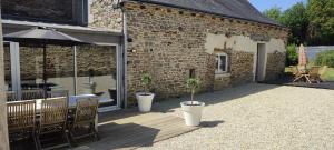 a patio with a table and chairs and an umbrella at Gîte L'hôtellerie in Trévron