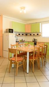 a kitchen with a table with chairs and a refrigerator at Magyar Tenger Pihenőház, for 2-8 person, 105 m2, garden, pool, free parking, 5 min from the Lake, Balatonakarattya in Balatonakarattya