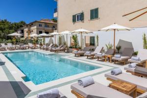 a pool with chairs and umbrellas next to a building at Hoposa Panorama in Port de Pollensa