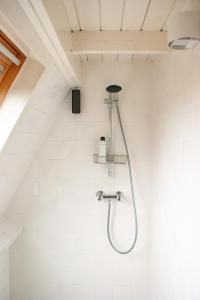 a shower in a bathroom with white tiles at Duinhuis Zout Hout in Egmond-Binnen