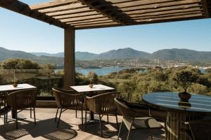 a patio with tables and chairs and a view of a lake at L'Hostellerie du Moulin des Oliviers in Olmeto