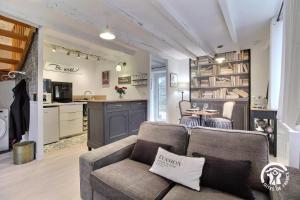 a living room with a couch and a kitchen at Le petit cottage in Ruffiac