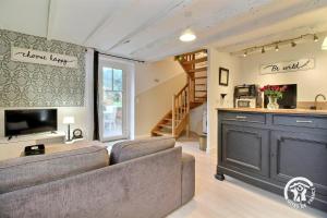 a living room with a couch and a staircase at Le petit cottage in Ruffiac
