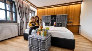 a woman and a child sitting on a bed at Familotel Der Böhmerwald in Eschlkam