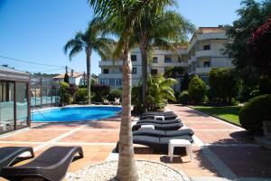 a row of lounge chairs next to a swimming pool at Hotel Spa Bosque Mar in Reboredo
