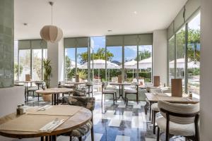 a restaurant with tables and chairs and large windows at Hoposa Panorama in Port de Pollensa