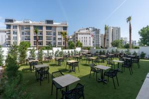 a group of tables and chairs on a lawn with buildings at Daylights Apart Otel in Antalya
