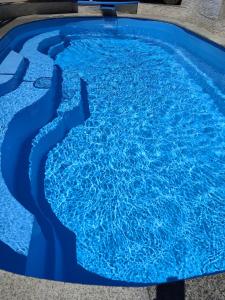 a swimming pool with blue water in the middle at Хотел PERLA in Strelcha