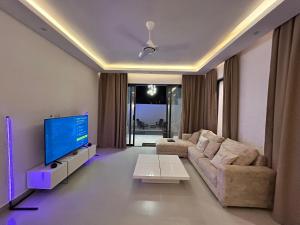 a living room with a couch and a flat screen tv at Amour Beach Villas in Paje
