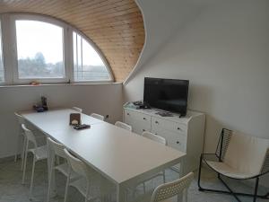 a room with a white table and chairs and a tv at Bükfürdő Bercsényi 13 apartmanház, Bükfalva in Bük