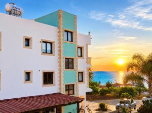 a building with the sunset in the background at JOANNA SUNSET APTS Pomos in Pomos