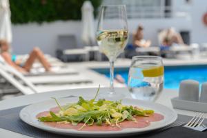 a plate of food on a table with a glass of wine at Apartamentos Vibra Tivoli in Playa d'en Bossa +39 photos