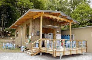 a small building with a deck with tables and chairs at Camping 3 étoiles - ccbfige in Pouancé