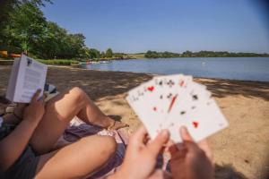 a woman laying on the beach reading a book and playing cards at Camping 3 étoiles - ccbfige in Pouancé