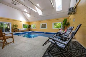 a living room with a swimming pool and two chairs at Lakefront Group Stay, Sleeps 19, Indoor Pool, Hot Tub, Arcades in Terre Haute