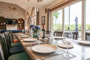 a long wooden table with plates and wine glasses at Lakefront Group Stay, Sleeps 19, Indoor Pool, Hot Tub, Arcades in Terre Haute
