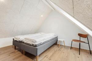a bed in a attic with a chair and a table at 9952-Hvide-Sande-Langsand-204 in Hvide Sande