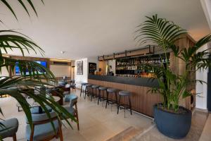 ein Restaurant mit einer Bar mit Stühlen und Pflanzen in der Unterkunft Luna Holiday Complex in Mellieħa