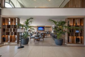eine Lobby mit Tischen, Stühlen und Pflanzen in der Unterkunft Luna Holiday Complex in Mellieħa