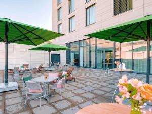 a patio with tables and chairs and green umbrellas at MÖVENPICK Hotel Stuttgart Messe & Congress in Stuttgart
