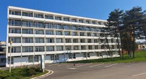 a large white building with a parking lot in front of it at Hotel Mures in Saturn