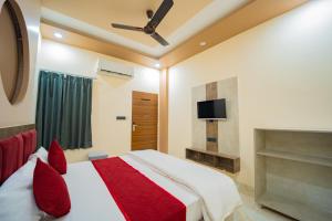 a bedroom with a bed with red pillows and a tv at Hotel Galaxy 700 - A Luxury Hotel Near KhatuShyamJi Temple in Khātu