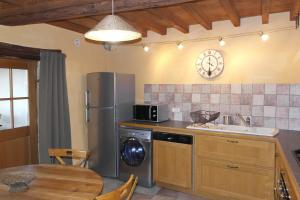 eine Küche mit einem Kühlschrank, einer Spüle und einem Tisch in der Unterkunft La Grunonde in Palogneux