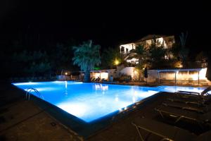 a large swimming pool at night with chairs around it at Bianco Olympico Beach Resort by Anayia All Inclusive Resorts in Vatopedi +28 photos