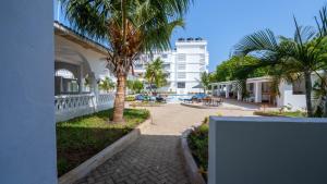 a walkway next to a building with palm trees at The Safiya Hotel, Diani Beach, "Formely Diani Palm Resort" in Diani Beach