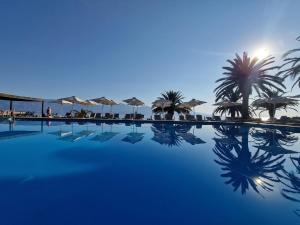 a swimming pool with palm trees and umbrellas at Long Beach Hotel & Resort in Lóngos