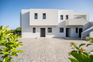 a white house with a driveway at Luxe benedenwoning Nula Kos in Kos