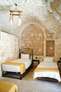 two beds in a room with a stone wall at Hızmalı OTEL in Urfa