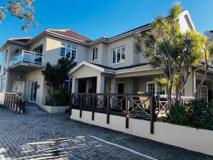 a large white house with palm trees in a driveway at A&A Guesthouse in Port Elizabeth