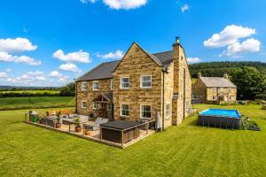an exterior view of a large brick house with a pool at Foxhall Farm in Thirsk