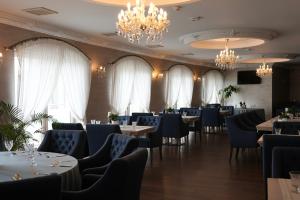 a dining room with tables and chairs and chandeliers at Hotel Kiston in Sulęczyno