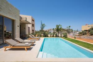 a swimming pool with chaise lounges and chairs next to a house at La Divina Luxury Villas with Heated Pool in Daratso
