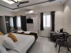 a bedroom with a bed and a table and a desk at Sri Padmavati Pleasants in Palni