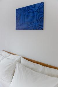 a white bed with a blue painting on the wall at La Stazione Formia in Formia